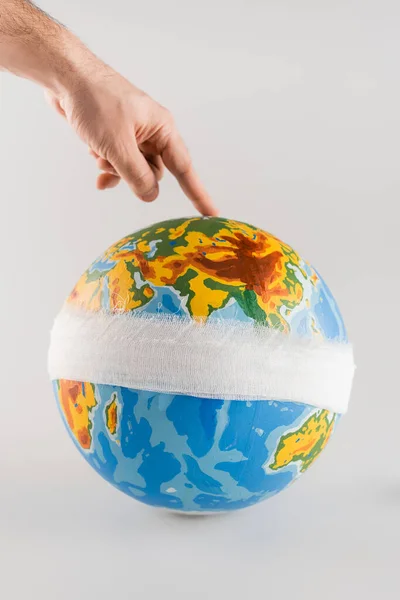 Vista recortada del hombre tocando globo vendado en gris, concepto de ecología - foto de stock