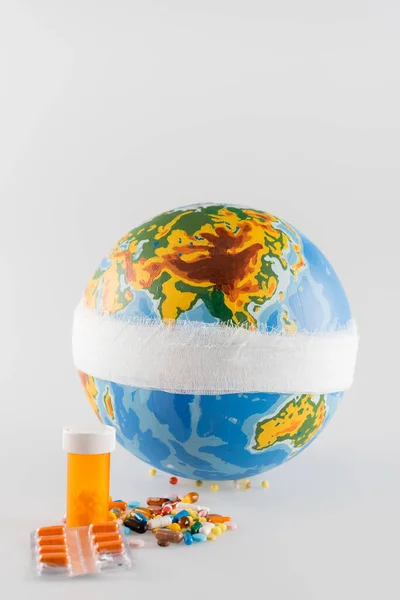 Bandaged globe near pills on grey background, ecology concept — Stock Photo