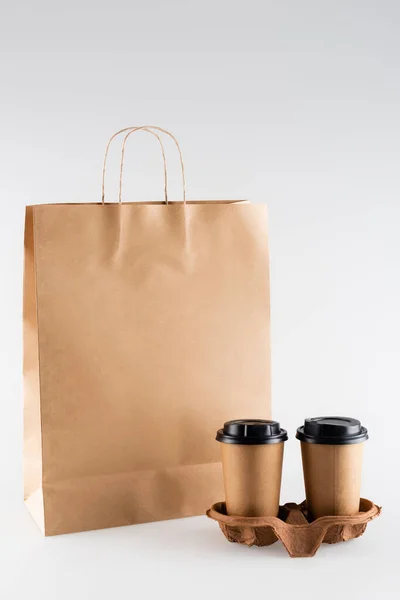 Bolsa de papel y vasos desechables en gris, concepto de ecología - foto de stock