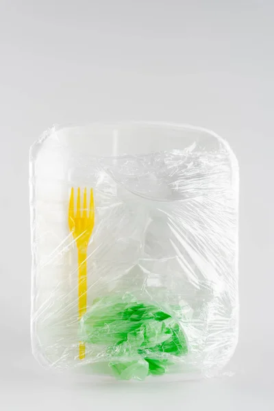 Вид сверху пластиковой пластины, вилки и мешка упакованы в целлофан, экологическая концепция — стоковое фото