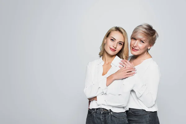 Young, smiling woman touching hand of stylish mother while looking at camera isolated on grey — Fotografia de Stock