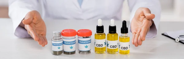 Cropped view of african american doctor pointing with hands at bottles with medical cannabis and cbd, banner — Stock Photo