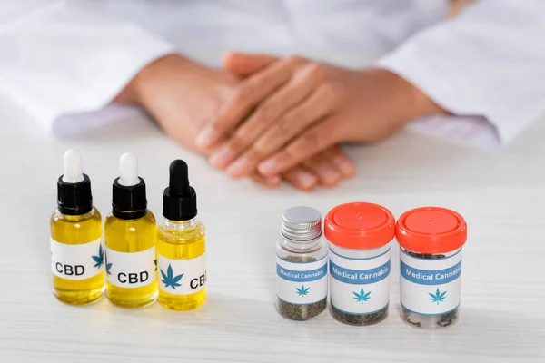 Cropped view of doctor near bottles with legal cbd and medical cannabis — Stock Photo