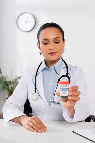 Medico afroamericano con stetoscopio bottiglia con lettering cannabis medica in clinica — Foto stock