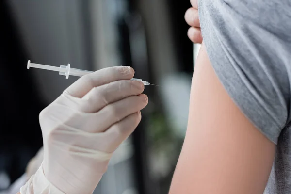 Cropped view of doctor holding syringe near patient during vaccination — Stock Photo