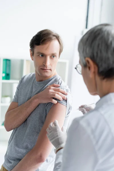 Patient qui consulte un médecin avec une seringue pendant la vaccination — Photo de stock