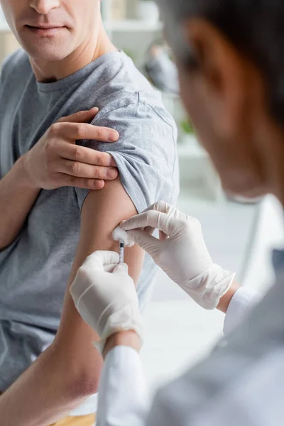 Médico sosteniendo jeringa y algodón durante la vacunación del paciente - foto de stock