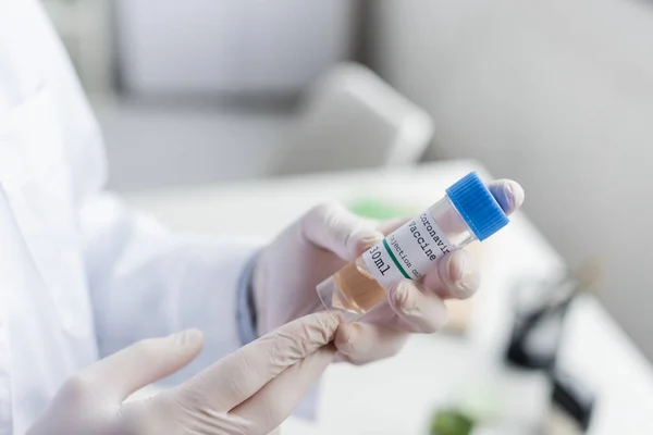 Cropped view of doctor in white coat and latex gloves holding vaccine — Stock Photo