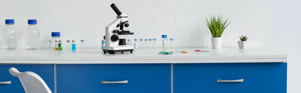 Вакцини, таблетки та мікроскоп на столі в лабораторії, банер — стокове фото