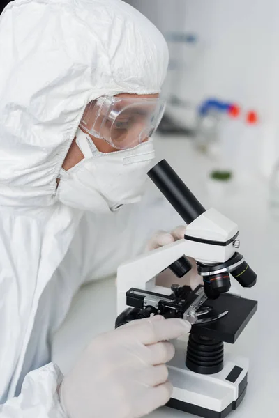 Вчений в латексних рукавичках і окулярах з використанням мікроскопа в лабораторії — стокове фото