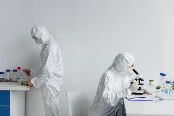 Вчені в костюмах з туманом, що працюють з вакцинами в лабораторії — стокове фото
