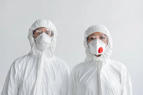 Вчені в костюмах і масках, які дивляться на камеру ізольовані на сірому — стокове фото