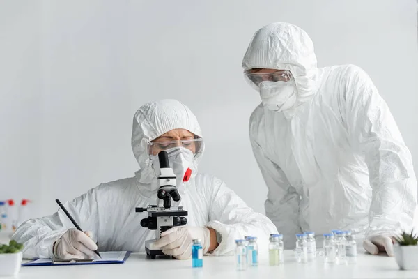 Вчені досліджують вакцину і пишуть на кишені в лабораторії — стокове фото