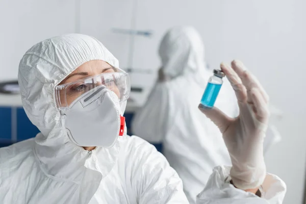 Scientist holding jar with vaccine on blurred foreground while working in laboratory — Stock Photo