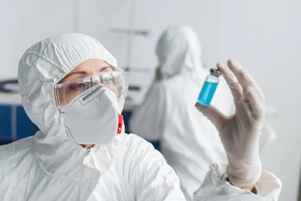 Вчений тримає банку з вакциною на розмитому передньому плані під час роботи в лабораторії — стокове фото