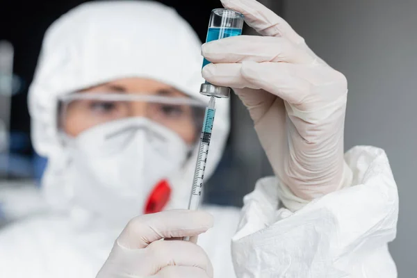 Scientist on blurred background picking up vaccine in syringe — Stock Photo