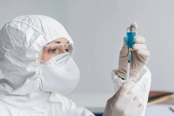 Scientist in protective uniform picking up vaccine in syringe in laboratory — Stock Photo