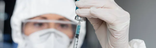 Шприц і вакцина в руках вченого на розмитому тлі, банер — стокове фото