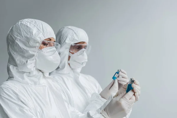 Вчений в костюмі і окулярах тримає вакцину поблизу колеги — стокове фото
