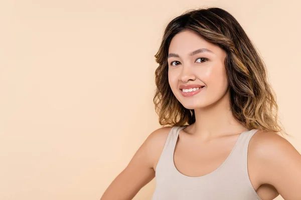 Young asian woman with perfect skin smiling at camera isolated on beige — Stock Photo