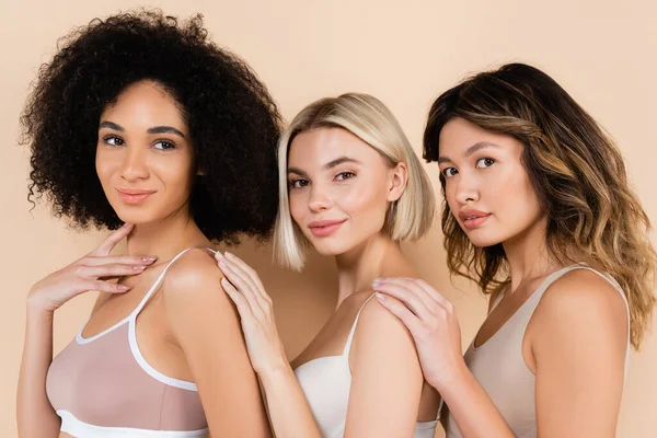 Jóvenes mujeres interracial en ropa interior posando en beige - foto de stock