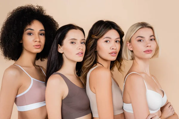 Young interracial women in bras looking at camera isolated on beige — Stock Photo