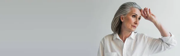 Femme d'âge moyen avec la main près du front isolé sur gris, bannière — Photo de stock