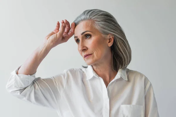 Femme d'âge moyen avec la main près du front isolé sur gris — Photo de stock