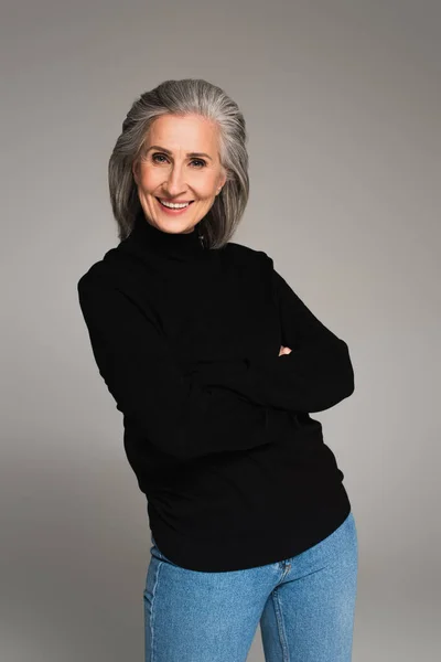 Smiling woman with crossed arms looking at camera isolated on grey — Stock Photo