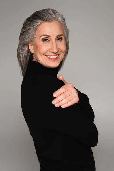 Портрет женщины в черном свитере, улыбающейся изолированно на сером — стоковое фото