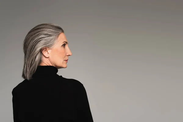 Side view of mature woman in turtleneck looking away isolated on grey — Stock Photo