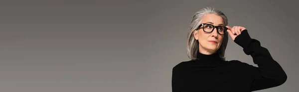 Femme tenant des lunettes et regardant loin isolé sur gris, bannière — Photo de stock