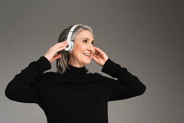 Mulher alegre usando fones de ouvido isolados em cinza — Fotografia de Stock