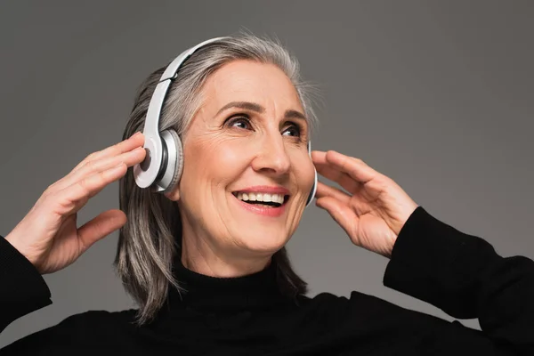 Mujer sonriente usando auriculares aislados en gris - foto de stock