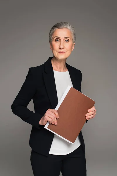 Ділова жінка в офіційному носінні тримає паперову теку ізольовано на сірому — стокове фото