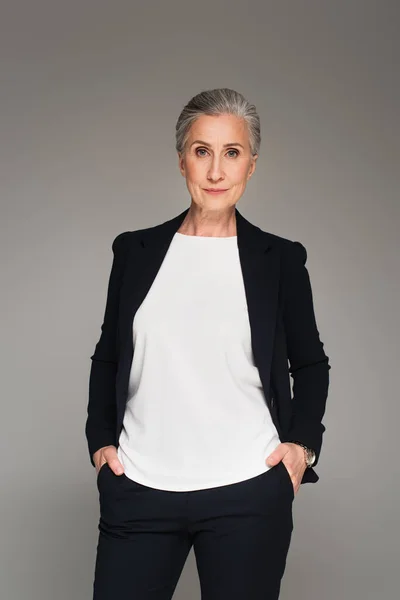 Grey haired businesswoman looking at camera isolated on grey — Stock Photo