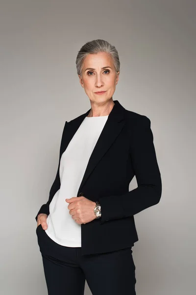 Mature businesswoman in formal wear looking at camera isolated on grey — Stock Photo