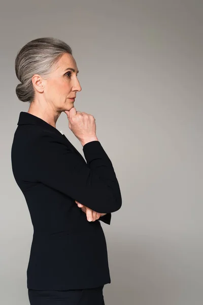 Vue latérale de coûteuse femme d'affaires mature regardant loin isolé sur gris — Photo de stock