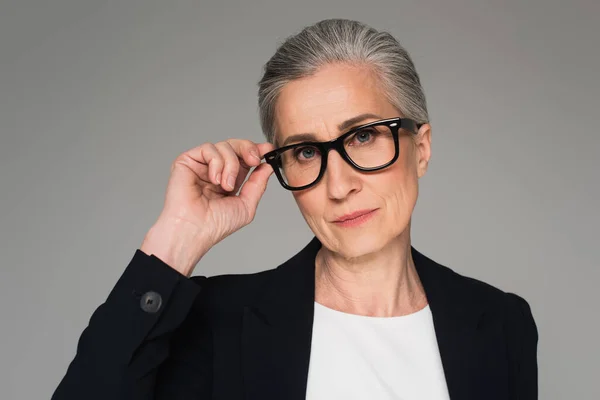 Reife Geschäftsfrau mit Brille blickt in Kamera isoliert auf grau — Stockfoto