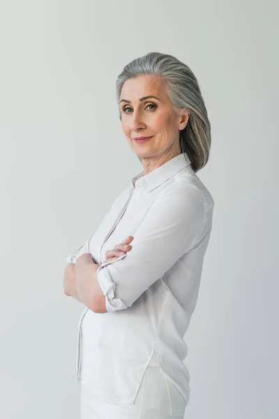 Grauhaarige Frau in weißen Kleidern blickt vereinzelt in die Kamera — Stockfoto