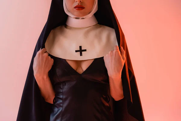 Vista cortada de freira sexy em vestido de couro preto no fundo rosa — Fotografia de Stock