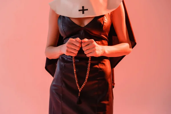 Vue partielle de nonne en robe sexy tenant des perles de prière isolées sur rose — Photo de stock