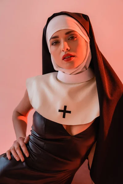 Sinnliche Nonne in sexy Kleid schaut auf Kamera isoliert auf rosa — Stockfoto