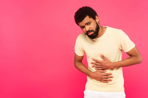 Displeased african american man suffering from stomach ache isolated on pink — Stock Photo