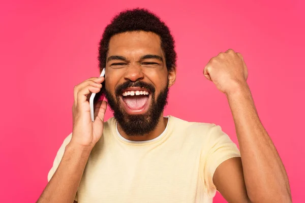 Aufgeregter afrikanisch-amerikanischer Mann spricht auf Smartphone isoliert auf rosa — Stockfoto