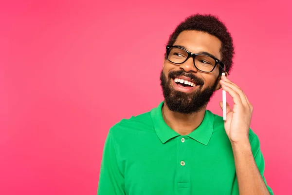 Афроамериканський чоловік у зеленій футболці говорить на смартфоні ізольовано на рожевому — стокове фото