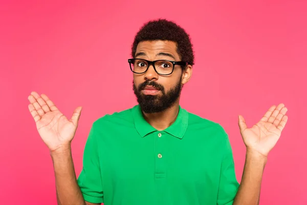 Hombre afroamericano en gafas apuntando con las manos aisladas en rosa - foto de stock