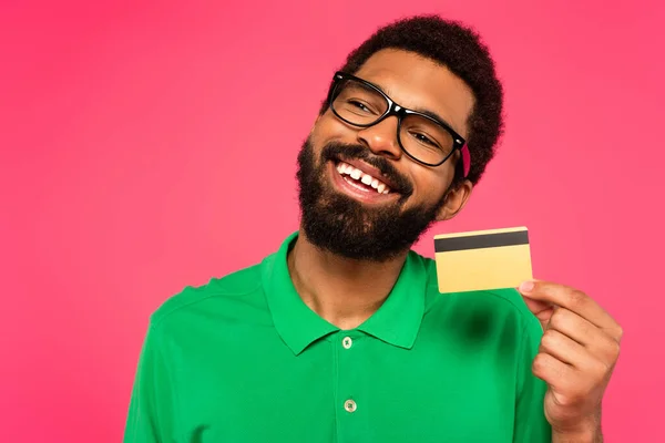 Piacere afro americano uomo in occhiali con carta di credito isolato su rosa — Foto stock