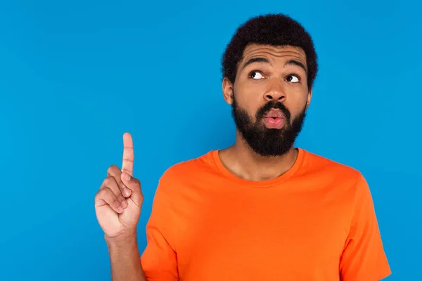 Shocked african american man pointing up isolated on blue — Stock Photo