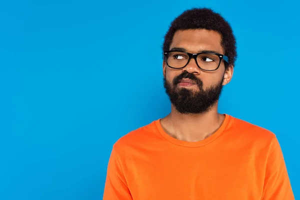 Doubtful african american man in glasses isolated on blue — Stock Photo